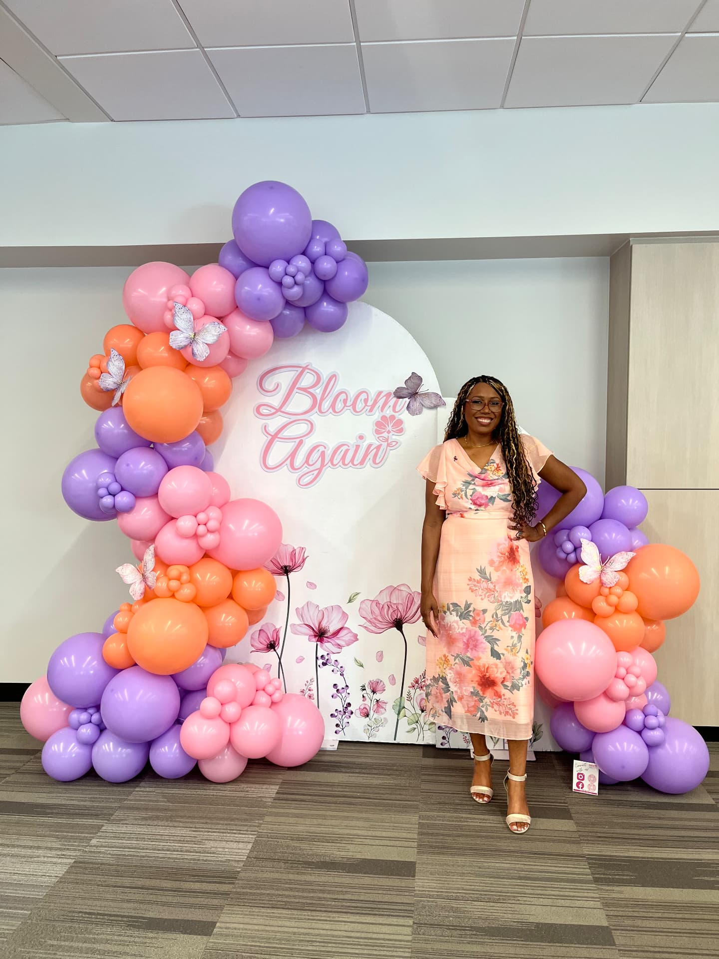 Jasmine Trevino standing beside a Bloom Again floral balloon backdrop